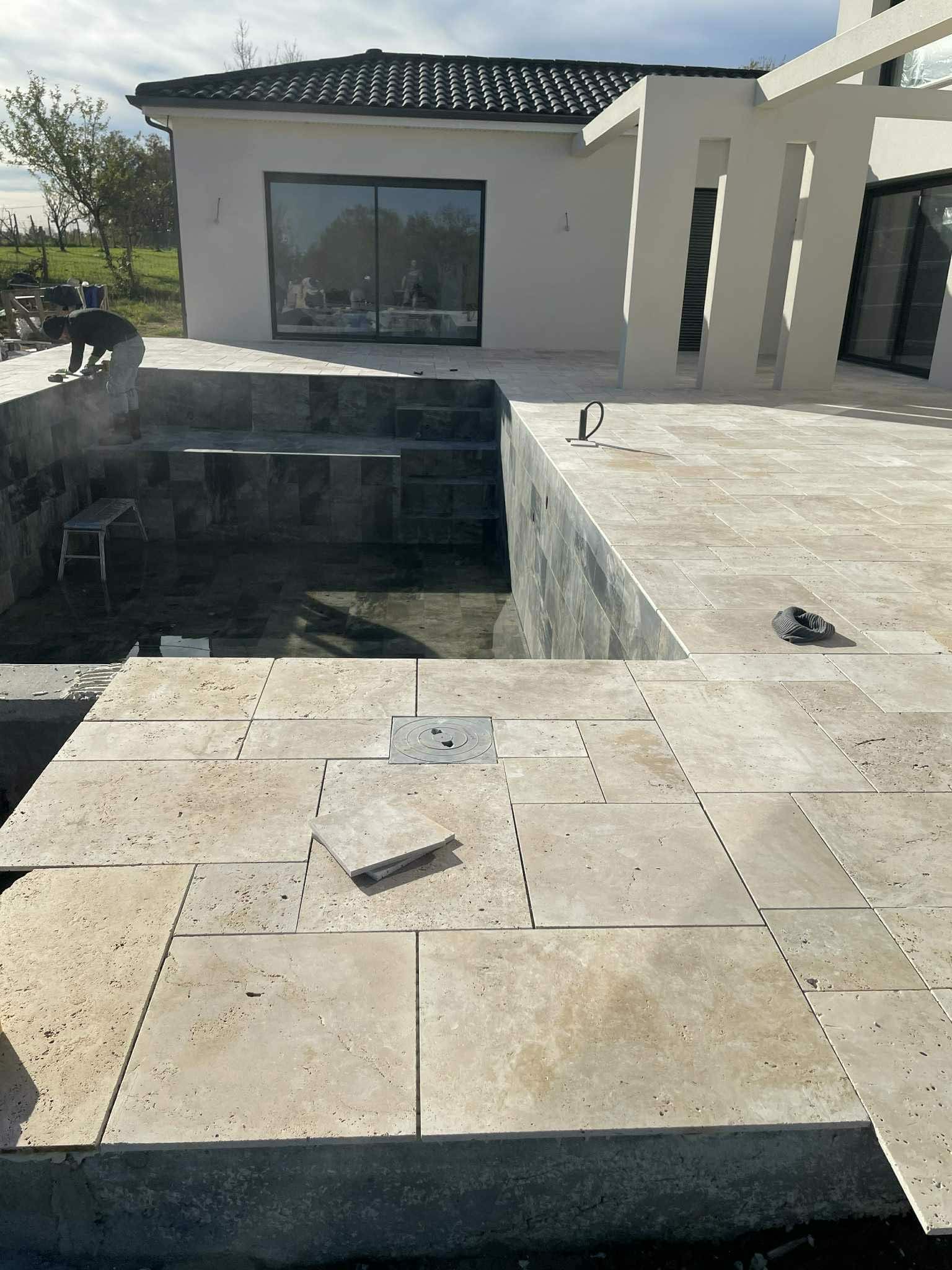 Pose de carrelage dans un bassin de piscine en cours de construction